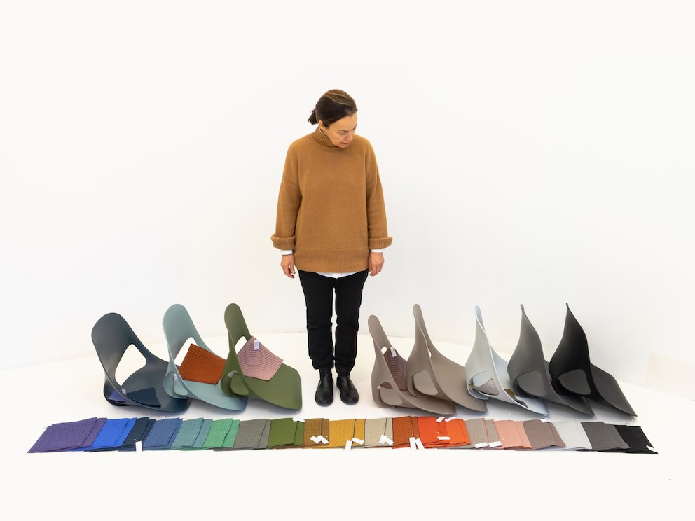 Carola Zwick from Studio 7.5 standing and looking at the shell and material colours available for the Zeph chair.