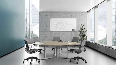 An enclosed meeting spaces setting featuring a Shift Levels guitar pick table with Setu Chairs.