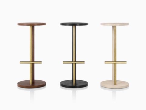 Three Spot Stools of different heights, featuring a circular seat and base connected by two parallel legs of wood and metal. 