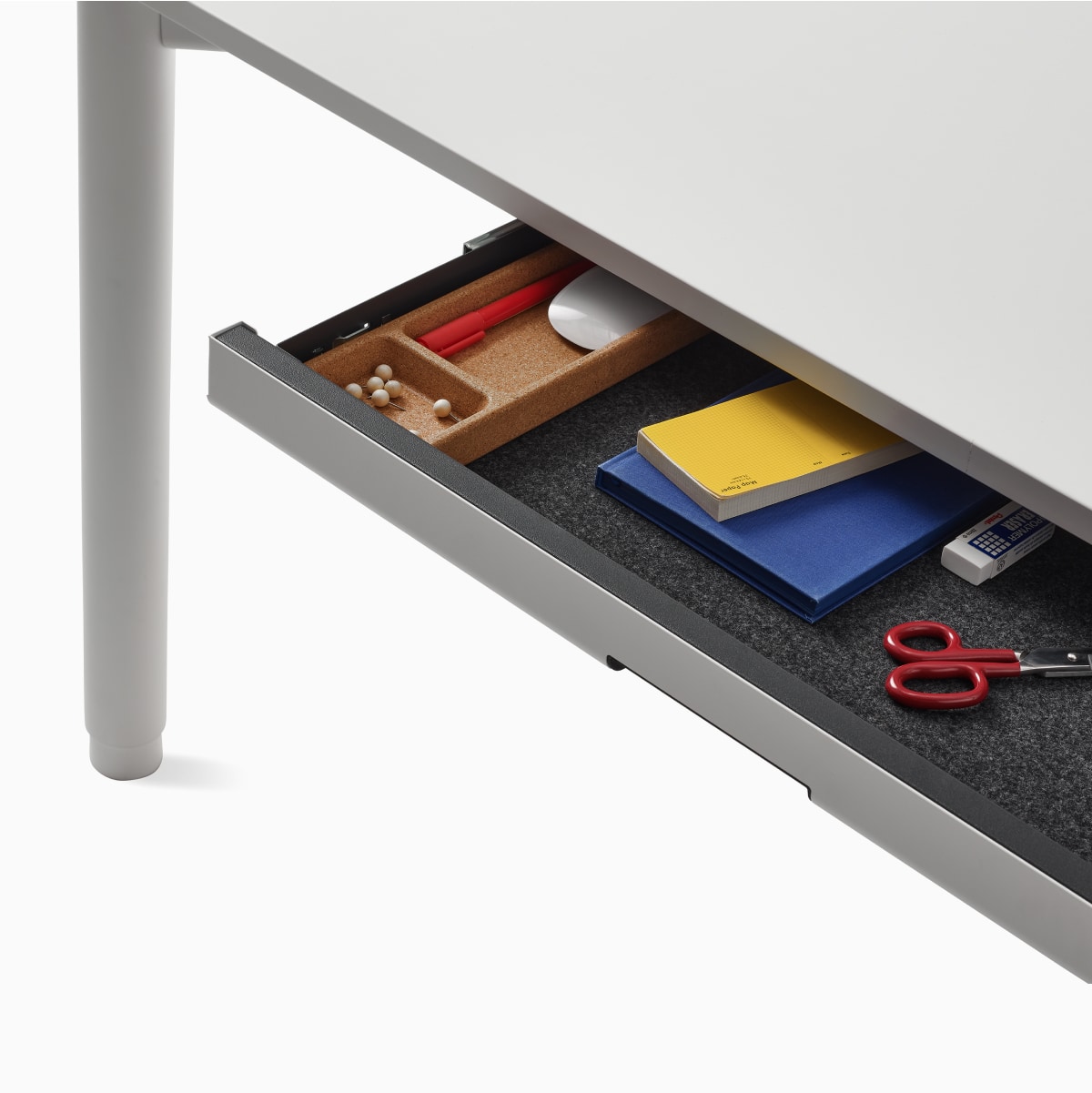 Detail of a storage drawer interior shown on a white four leg height-adjustable table.
