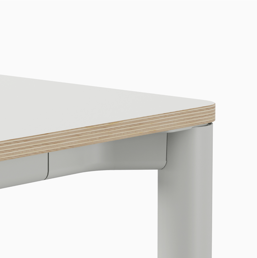 Detail of the plywood edge on Spout sit-to-stand table with white top and light grey base.