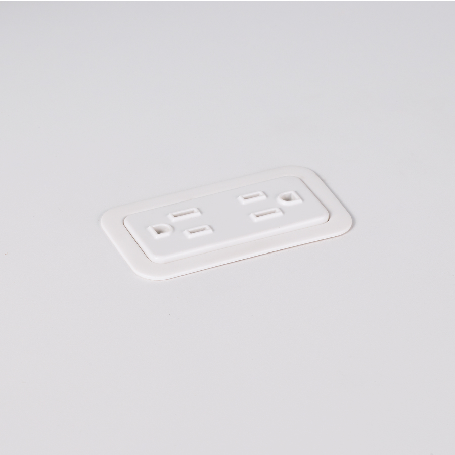 A close-up view of Logic Mini with two power outlets integrated into the top of a white laminate work surface.