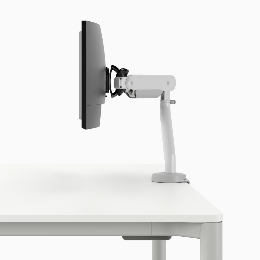 Detail of a monitor arm on the Spout Sit-to-Stand Table with white surface and light grey base.