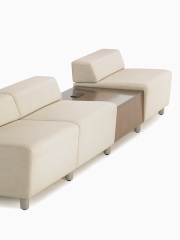 A straight configuration of three beige, low-back Steps Lounge System modules with an intervening surface offering power access.