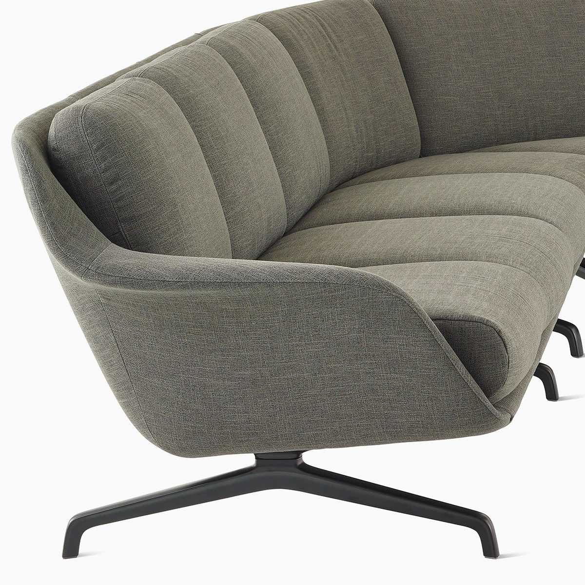 Un divano Striad a tre posti con schienale basso con curva interna in una configurazione componibile color grigio scuro.