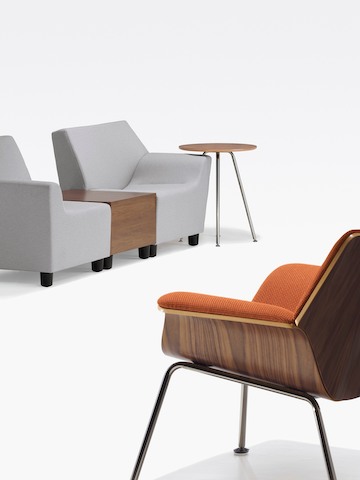 An orange Swoop lounge chair and two gray Swoop modular components on either side of a coordinating box table. An orange Swoop lounge chair and two gray Swoop modular components on either side of a coordinating box table.