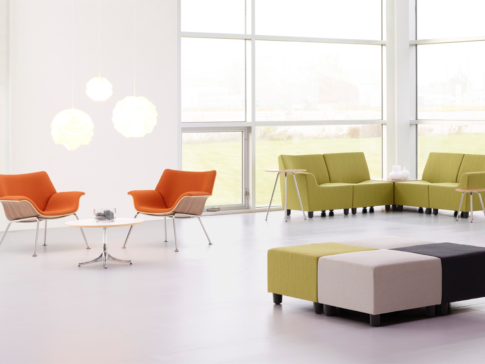 Espreguiçadeiras Orange Swoop e assentos modulares Swoop em verde em um espaço de encontro casual.