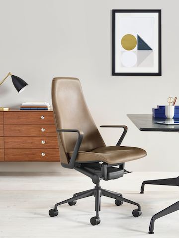 Una oficina ejecutiva con una silla Taper de cuero marrón, una mesa rectangular Eames y un gabinete del Nelson Thin Edge Group.