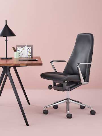 A black leather Taper Chair paired with a rectangular table with a wood top. A black leather Taper Chair paired with a rectangular table with a wood top.