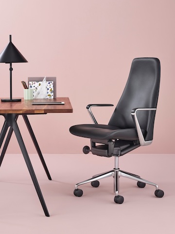 Cadeira executiva de couro preto Taper em um escritório privado contemporâneo.