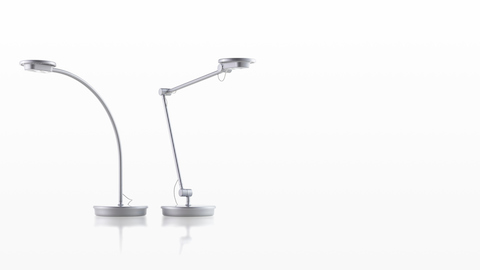 Two silver Tone Personal Lights, one with a single curved arm and one with an articulating arm.