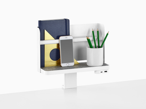 Une étagère Ubi attachée avec une toile de fond prend en charge un livre, un smartphone, un gobelet à crayons et un module d'alimentation USB.