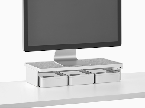 A freestanding monitor sits on a Ubi Monitor Platform Shelf with a USB power module and three storage boxes below.