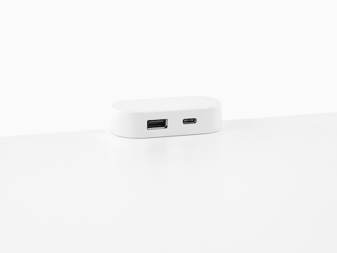 Um módulo de alimentação USB Ubi acoplado ao topo de uma superfície de trabalho e contendo duas portas USB de diferentes tamanhos.