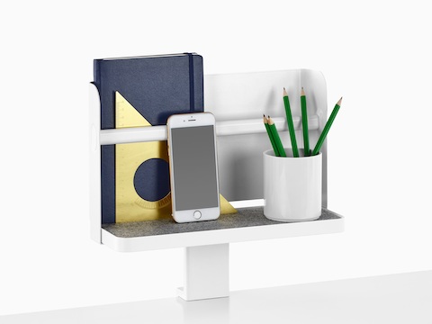 Una mensola allegata Ubi con uno sfondo supporta un libro, uno smartphone e una tazza per le matite.