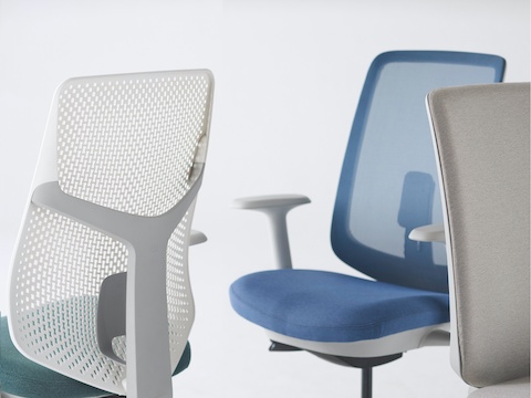 A close-up view of a Verus Chair with a green Triflex back, a Verus Chair with a blue upholstered seat and blue suspension back, and a Verus Chair with a grey upholstered back.