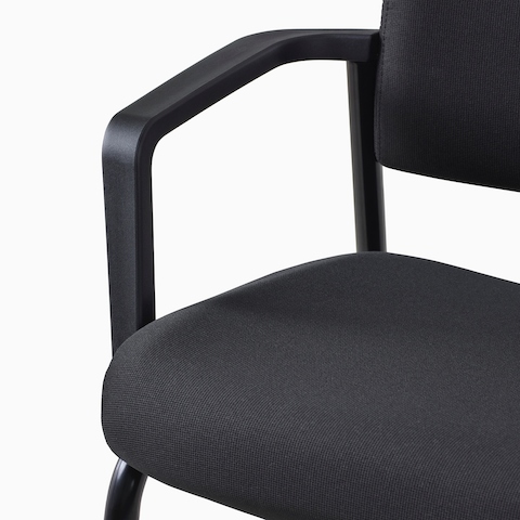 A close-up view of a Verus Side Chair's black upholstered seat with arms.