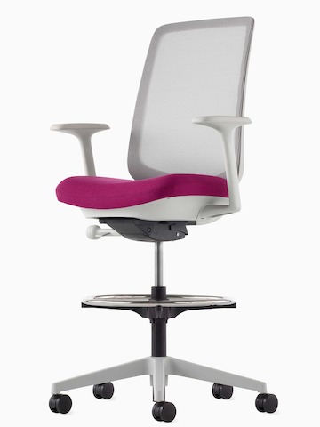 Ein grauer Verus Hocker mit Membran-Rückenlehne und rosa Sitzfläche, im schrägen Winkel betrachtet.