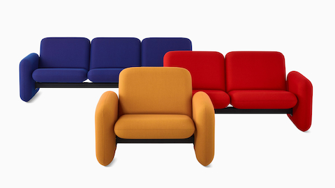 A dark yellow Wilkes Modular Sofa Group Chair faces forward in front of a Wilkes Modular Sofa Group 2-Seat Sofa in red and a Wilkes Modular Sofa Group 3-Seat Sofa in blue.