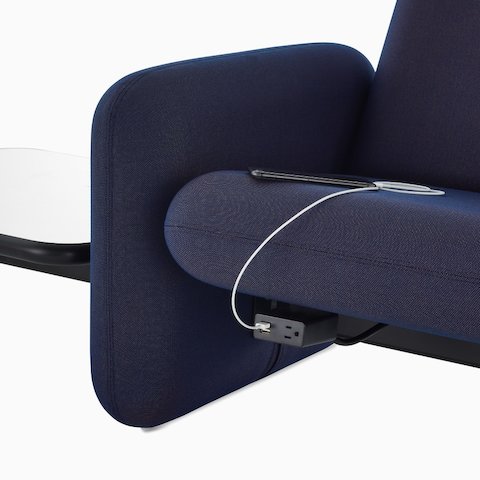 A close up view of a phone charging in a power module on a Wilkes Modular Sofa Group Sofa in dark blue.