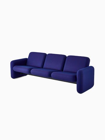 Vista frontal angular de un sofá de 3 asientos del conjunto de sofás modulares Wilkes en azul.
