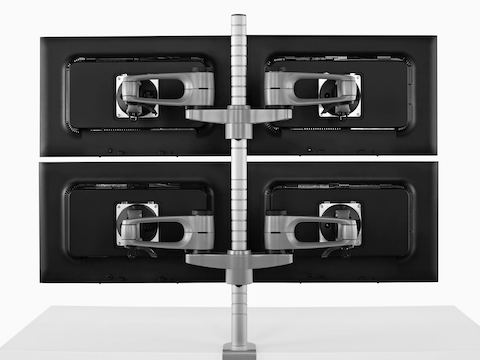 Vista posterior de cuatro monitores conectados a un único poste del brazo del monitor Wishbone.