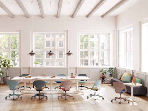 A meeting space featuring nine Zeph chairs in red, light blue and light brown that surround a Headway table and round side table.
