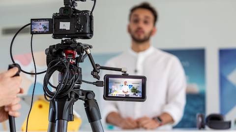 Een man die voor de camera presenteert achter een in hoogte verstelbaar Ratio bureau.