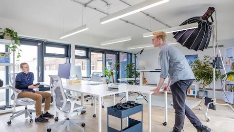 White OE1 mobile tables with mid-back Cosm chairs and a height-adjustable Ratio desk in the background.