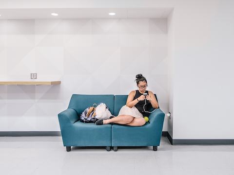 A student looks at her phone while seated in a Swoop lounge chair. 