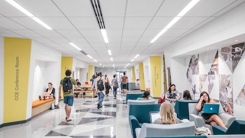 Students inside of a corridor with wall benches and lounge seating. 