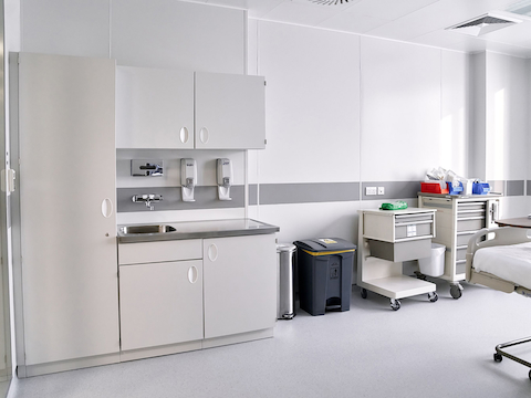 Very white and pristine hospital room with procedure and supply carts viewed from the front and placed against the wall.