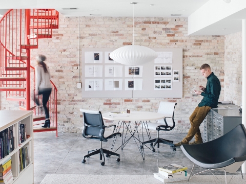 An open workspace with a red spiral staircase and pendant light. An open workspace with a red spiral staircase and pendant light.