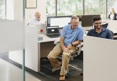 People sit at their computers inside of an open work space area.