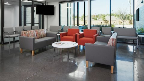 Lobby waiting area with Nemschoff Valor Side and Plus Chairs in gray, with Nemschoff Brava Classic Armchairs in orange and Nemschoff Brava Multiple Seating in gray seats and multicolored backs, with Nemschoff Palisade Coffee Table with a white top and silver legs.