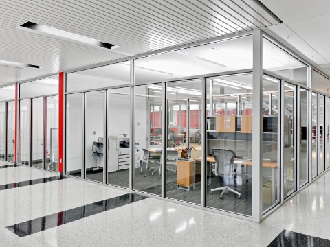 Divided workstations sit inside of glass divider walls. Divided workstations sit inside of glass divider walls.