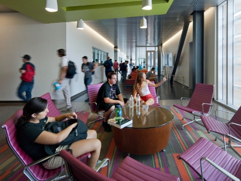 Students sit amonst Eames aluminum chairs placed near windows. 