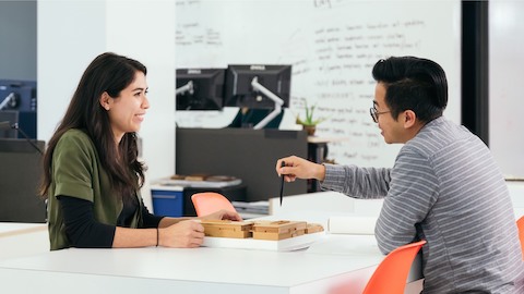 A man and a woman reviewing work at a hightop table.