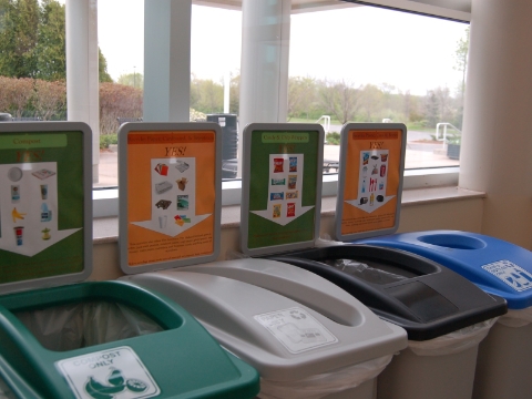 A row of recycle bins for different materials inside Grand Valley State University.