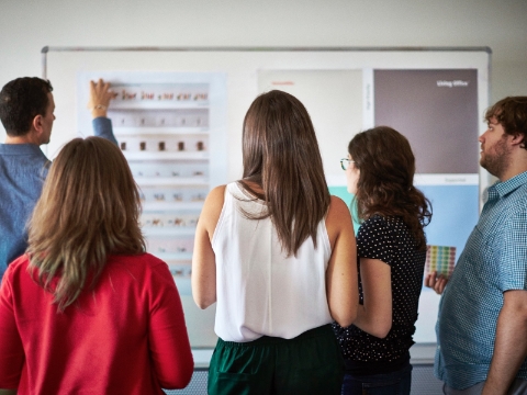 Kantoormedewerkers luisteren naar een presentatie van een collega.