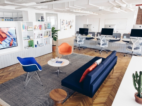 An office loung seating area sits near several workstations in the background.