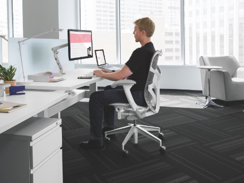 A man works at his computer while seated in a Mirra chair.