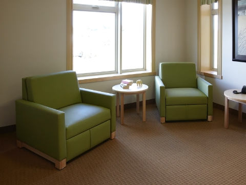 Two green Beaumont sleep chairs sit in a corner near a window. 