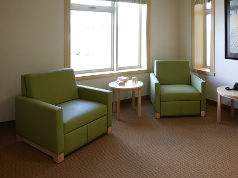 Two green Beaumont sleep chairs sit in a corner near a window. Two green Beaumont sleep chairs sit in a corner near a window.