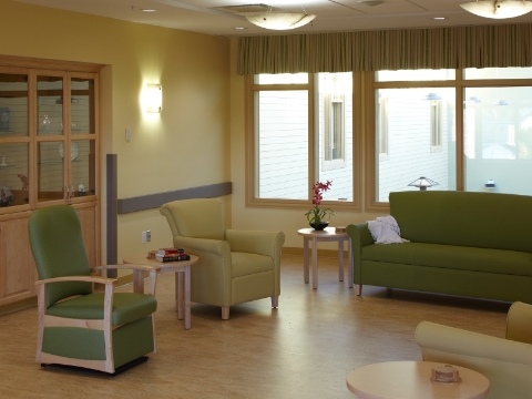 A green Torri Glider sits near matching lounge seating in a commons area. 