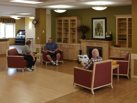 Residents and staff of an assisted living center mingle in a lounge area. 