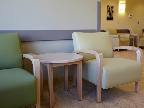 Two Nemschoff Collection chairs share an end table while placed against a wall. 