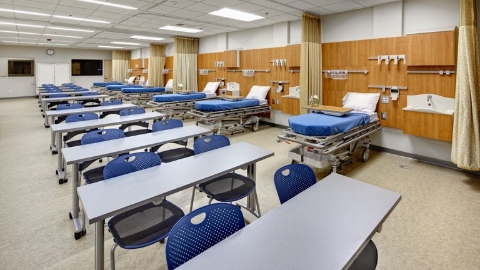 A healthcare classroom with mock patient rooms. Select to go to a case study featuring the Madonna University College of Nursing and Health.