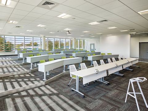 A presentation room features abundant natural light and rows of chairs and tables. 