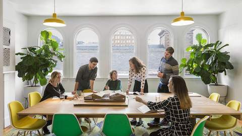 People talk at a large conference table inside an office meeting room.